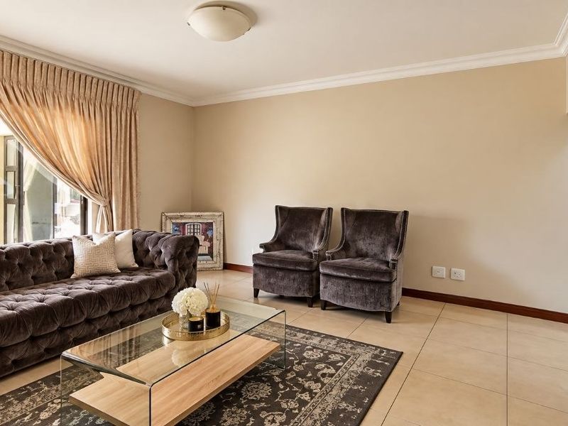 A well-maintained living room featuring neutral tiled flooring, ceiling cornicing, and a large sliding glass door providing access to the outdoor area.