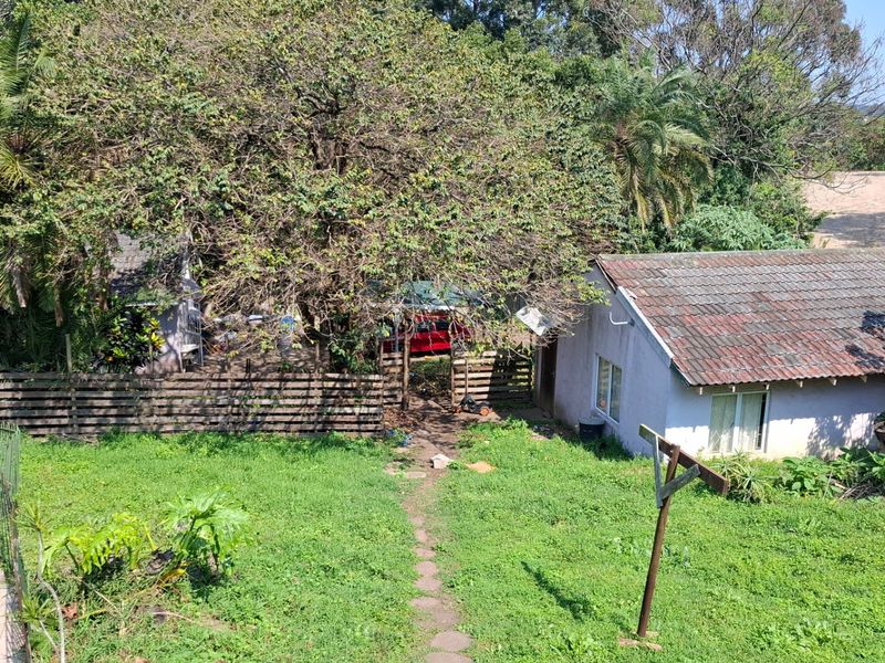 Rear view of the property featuring a tiled roof structure, a swimming pool, and a large garden area with mature trees.