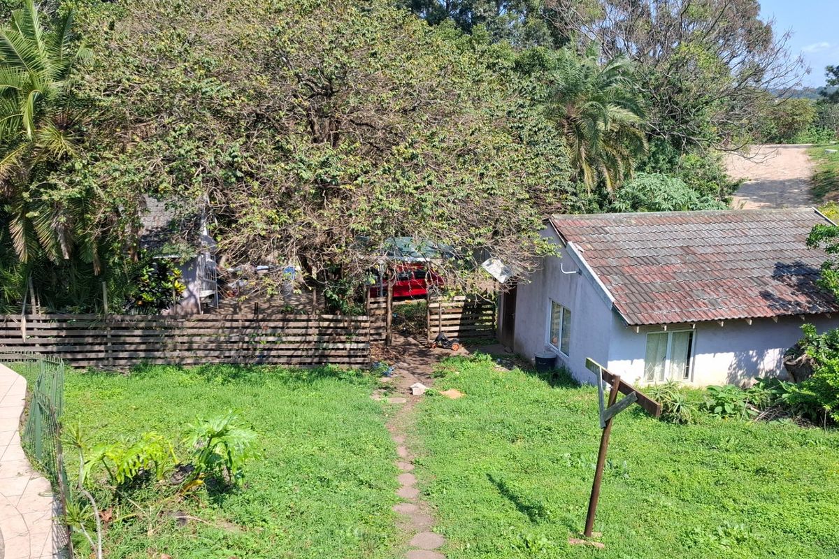 Rear view of the property featuring a tiled roof structure, a swimming pool, and a large garden area with mature trees.