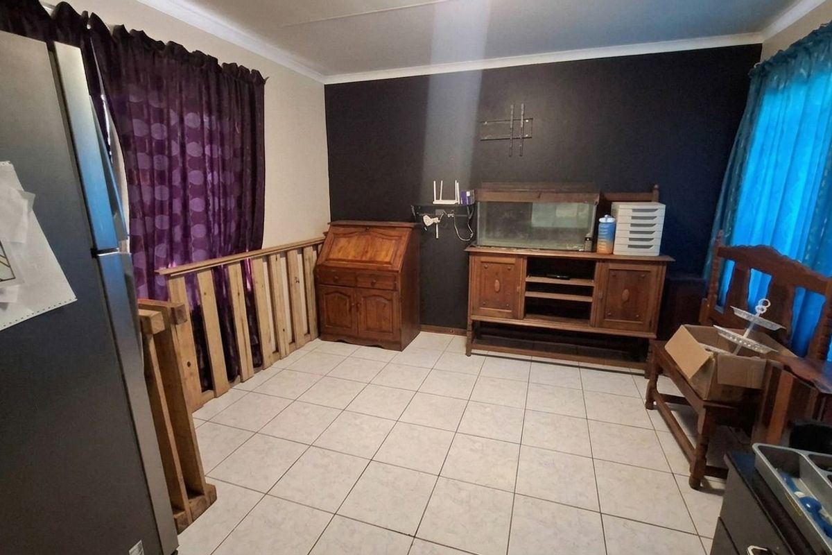 A living area featuring tiled flooring and a wooden balustrade, providing a functional space with neutral wall finishes.