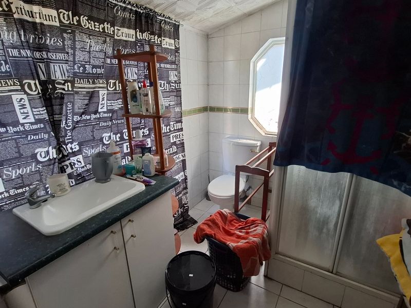A functional bathroom featuring a vanity with integrated sink, toilet, and a shower enclosure with tiled walls and flooring.