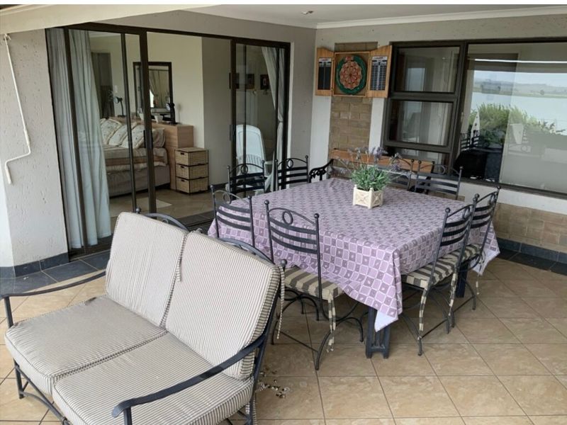 A covered patio area featuring tiled flooring, brick accents, and large sliding glass doors providing access to the interior living space.