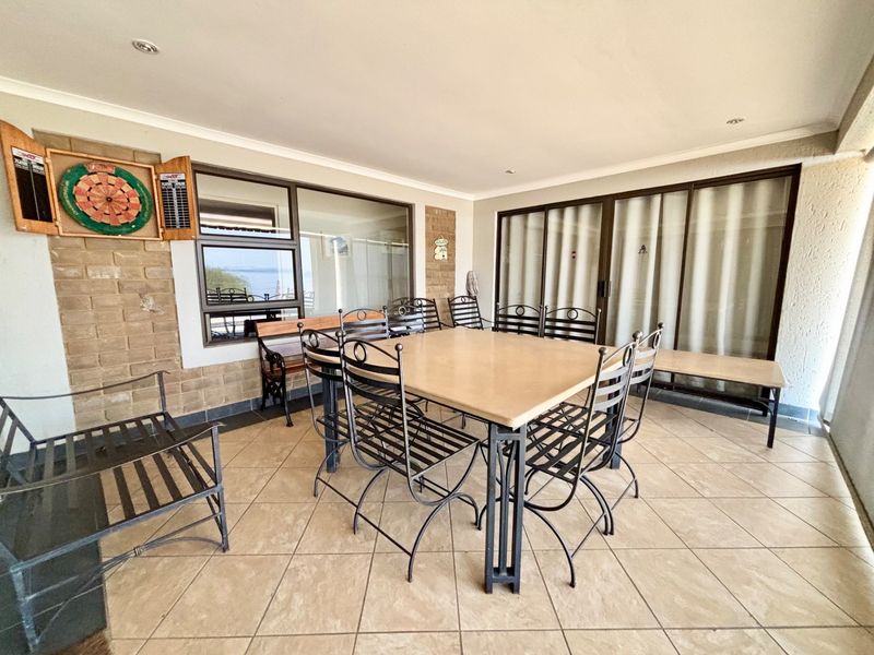 A spacious covered patio featuring tiled flooring, exposed brick accents, and large sliding glass doors providing seamless access to the interior living spaces.