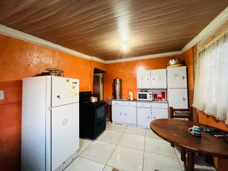 A functional kitchen featuring tiled flooring, built-in cabinetry, and a stove, offering potential for modernization and aesthetic updates.
