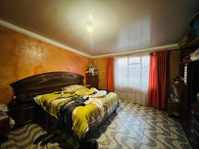 A bedroom featuring tiled flooring, security bars on the window, and decorative coving, requiring cosmetic updates to the wall finishes.