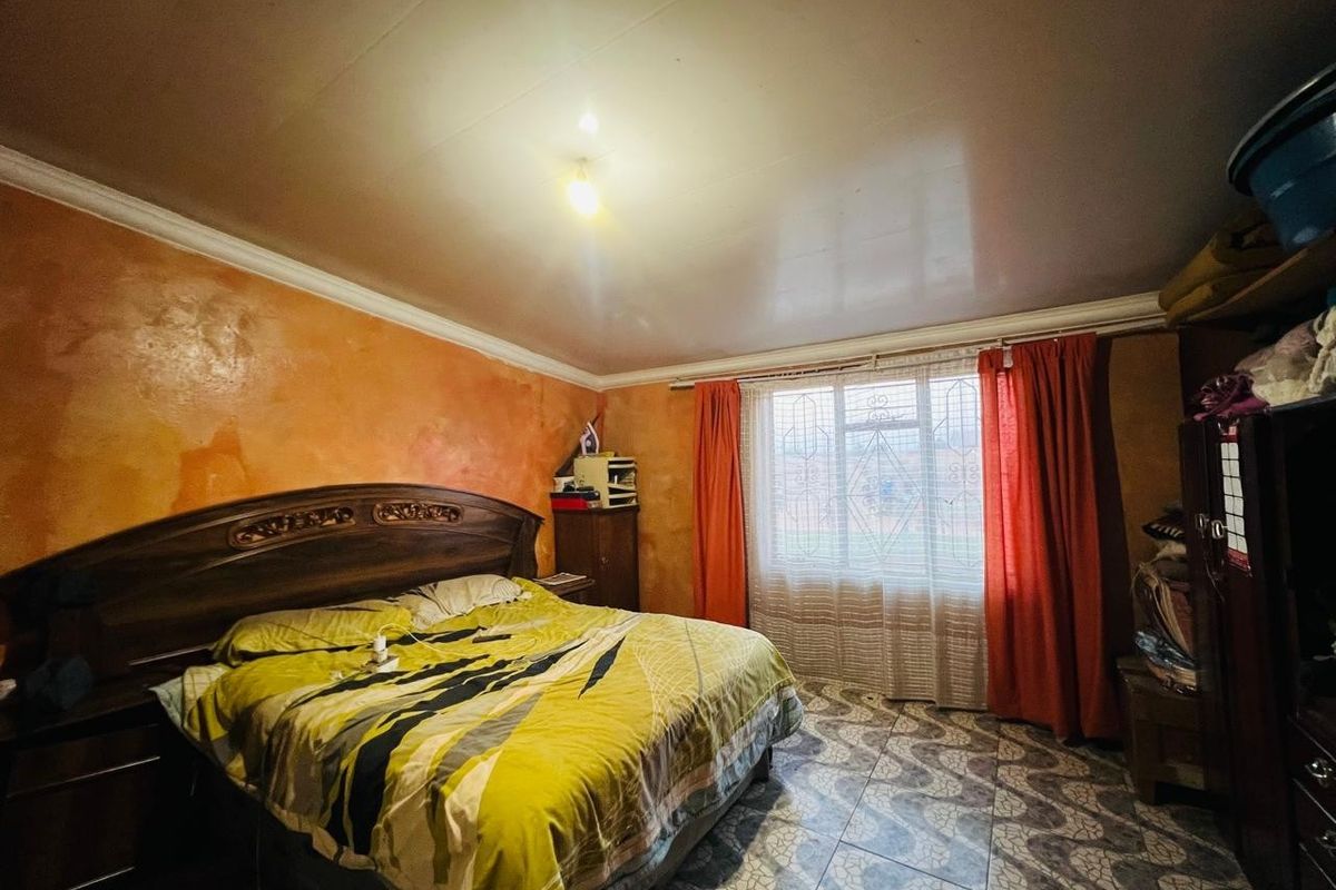 A bedroom featuring tiled flooring, a security gate on the window, and decorative ceiling cornicing, currently requiring cosmetic updates to the wall finishes.
