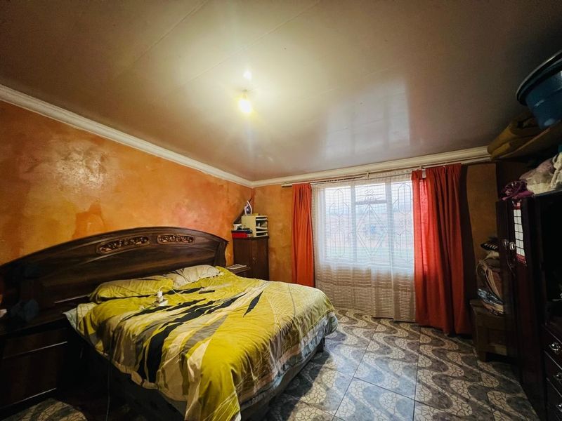 A bedroom featuring tiled flooring, a security gate on the window, and decorative ceiling cornicing, currently requiring cosmetic updates to the wall finishes.