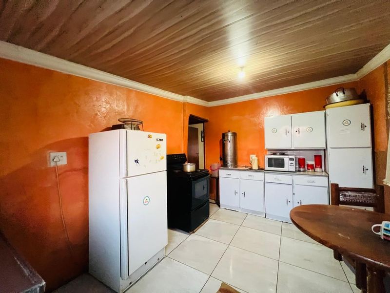 A functional kitchen featuring tiled flooring, built-in cabinetry, and a stove, offering a practical layout with potential for modern cosmetic updates.