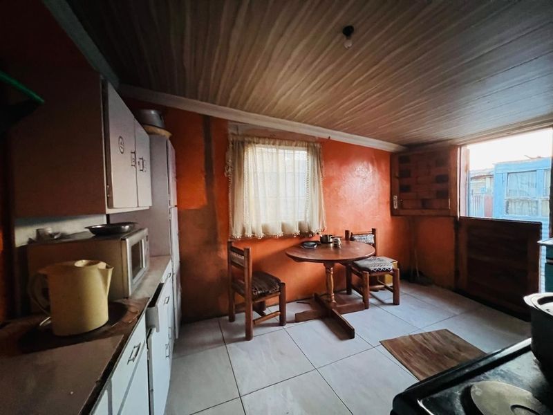 A dated kitchen featuring built-in cabinetry, tiled flooring, and a timber ceiling, requiring cosmetic updates to modernize the space.