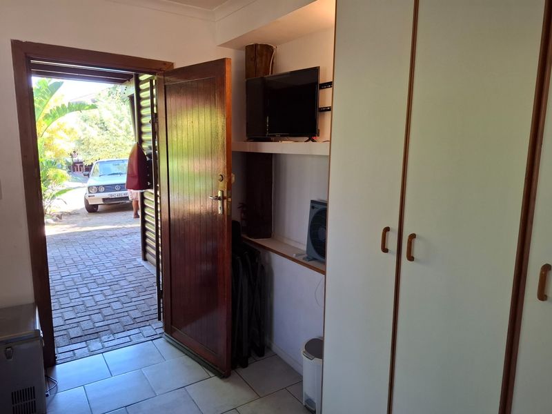 Entrance area featuring tiled flooring, built-in cupboards for storage, and a timber door providing direct access to the exterior driveway.
