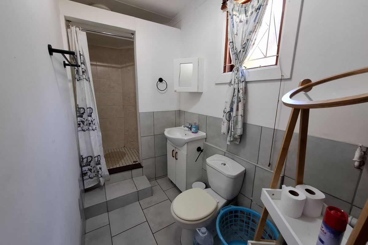 A functional bathroom featuring a shower cubicle, vanity basin, and toilet with neutral wall and floor tiling.