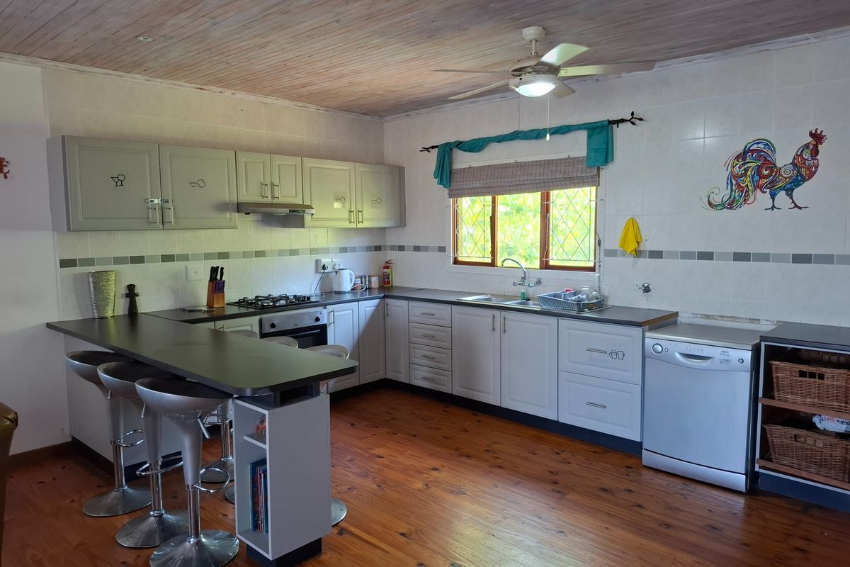 A functional kitchen featuring timber flooring, wood-paneled ceiling, built-in cabinetry, gas hob, and a breakfast bar counter.