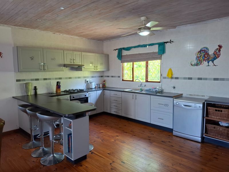 A functional kitchen featuring timber flooring, wood-paneled ceiling, built-in cabinetry, gas hob, and a breakfast bar counter.