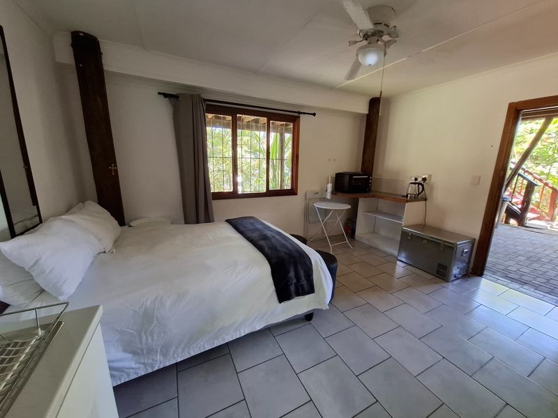 A bedroom featuring tiled flooring, a ceiling fan, and built-in shelving, with direct access to an outdoor area.