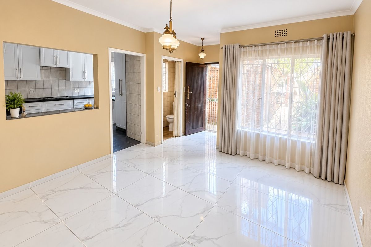 Bright and spacious living area featuring polished marble-look floor tiles, coved cornices, and a convenient pass-through window connecting to the kitchen.