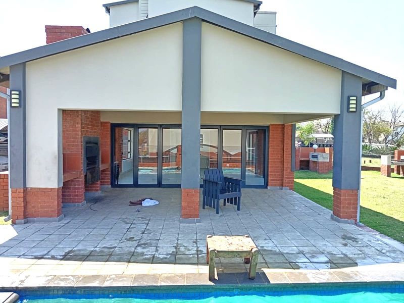 Covered patio area featuring a built-in braai, tiled flooring, and large sliding glass doors providing access to the interior living space.