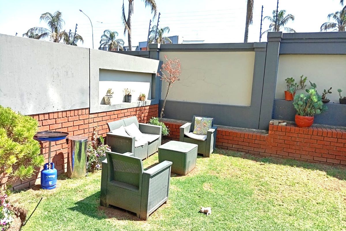 A private rear garden area featuring a well-maintained lawn, brick and concrete boundary walls, and integrated electric fencing for added security.