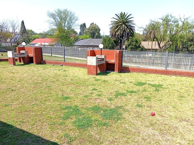 Communal garden area featuring built-in brick braai facilities and secure perimeter fencing.