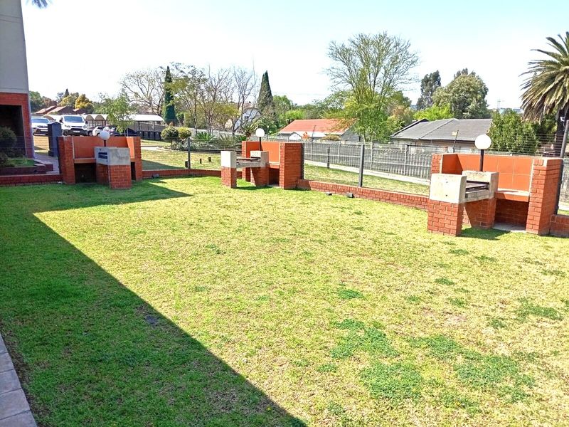 Communal garden area featuring multiple built-in brick braai stations and perimeter fencing, providing an outdoor space for residents.