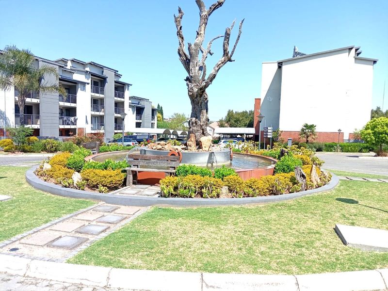 A landscaped communal garden area featuring a central water feature and paved walkways within an apartment complex.
