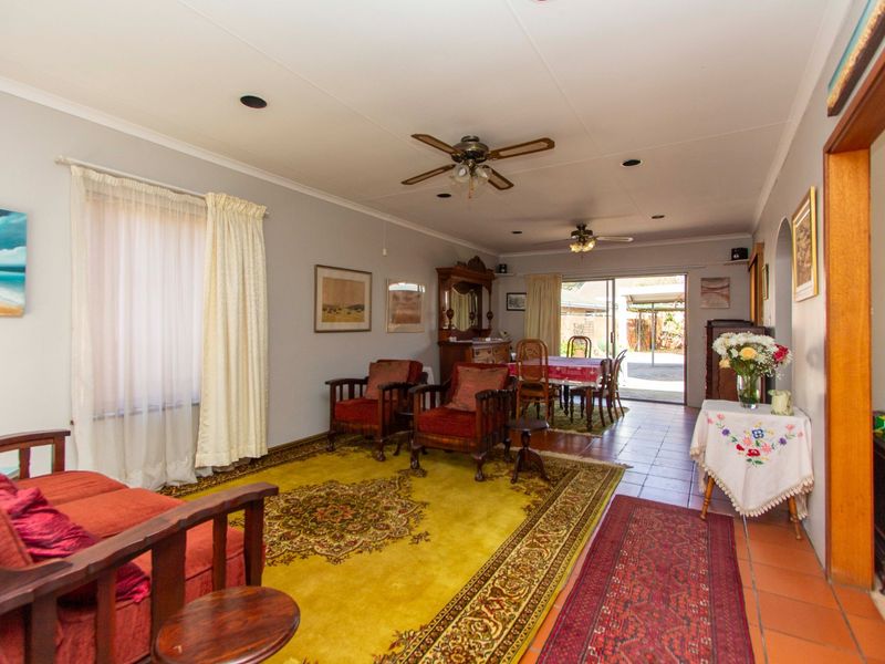 Spacious open-plan living and dining area featuring tiled flooring, ceiling fans, and direct access to the rear patio through sliding glass doors.
