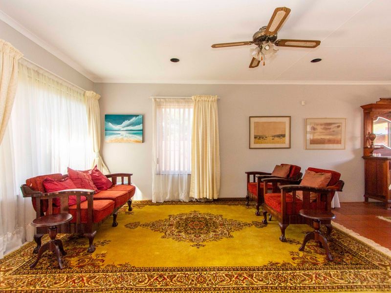 A spacious living room featuring a ceiling fan, recessed lighting, and large windows with neutral curtains, offering a comfortable and well-lit living space.