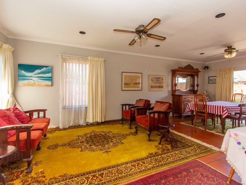 Spacious open-plan living and dining area featuring tiled flooring, ceiling fans, and recessed lighting with access to the outdoor area via sliding glass doors.