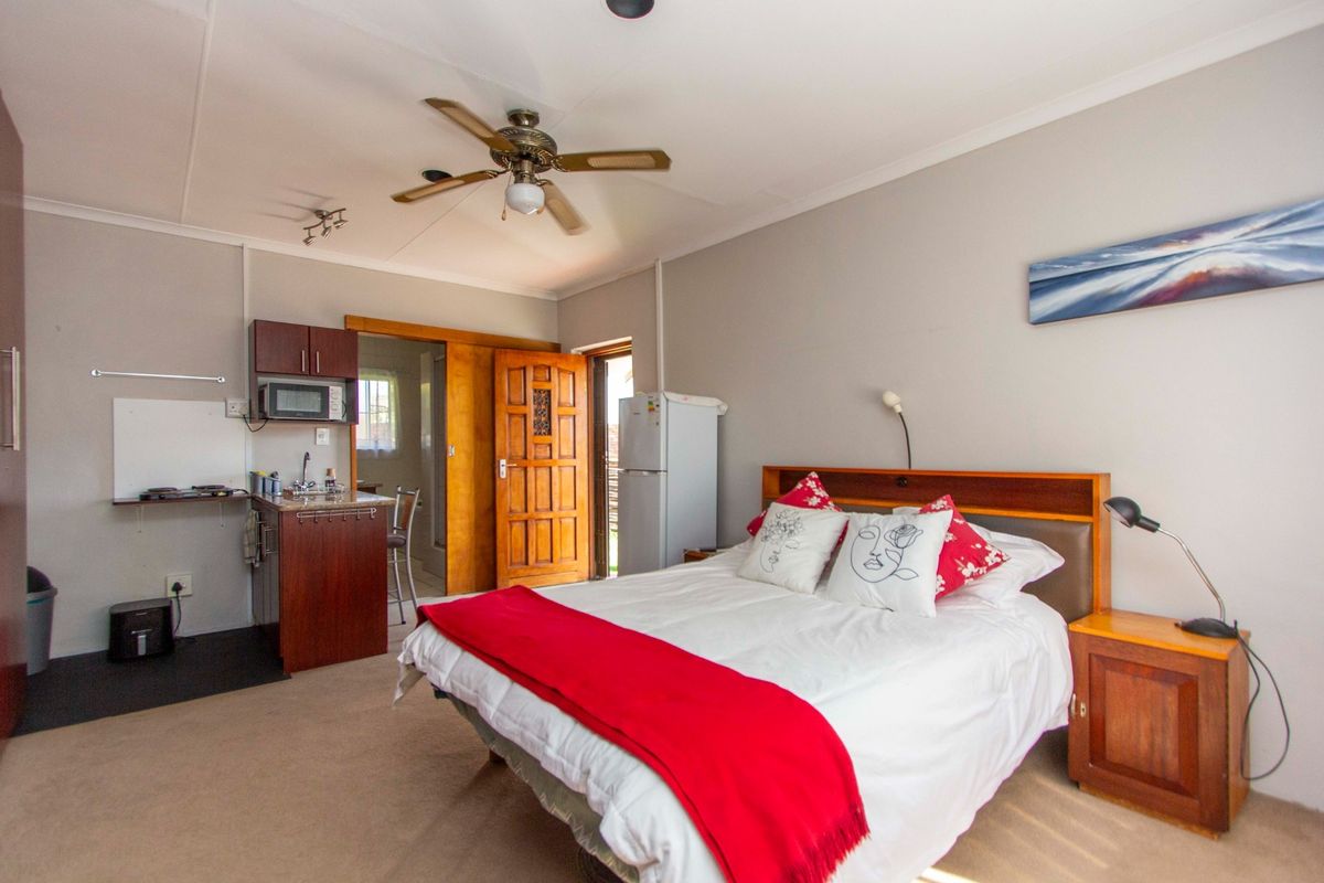 A bedroom featuring a compact built-in kitchenette area, ceiling fan, and direct access to an en-suite bathroom.