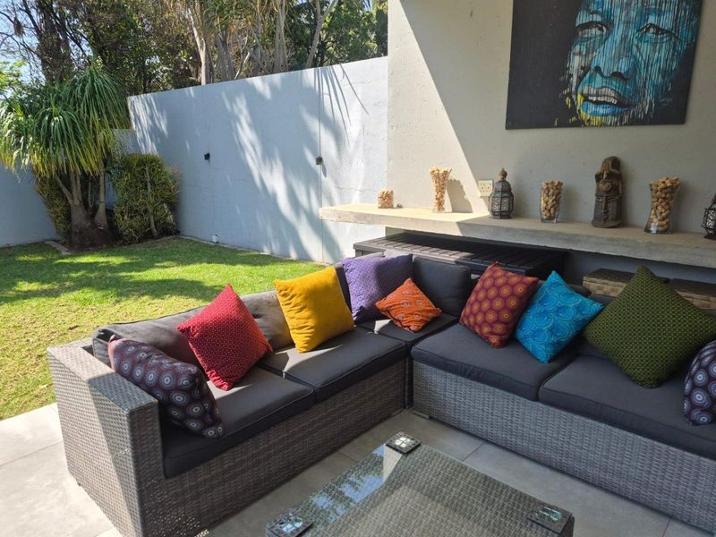 A covered patio area featuring a concrete floating shelf and tiled flooring, overlooking a private garden with a boundary wall.