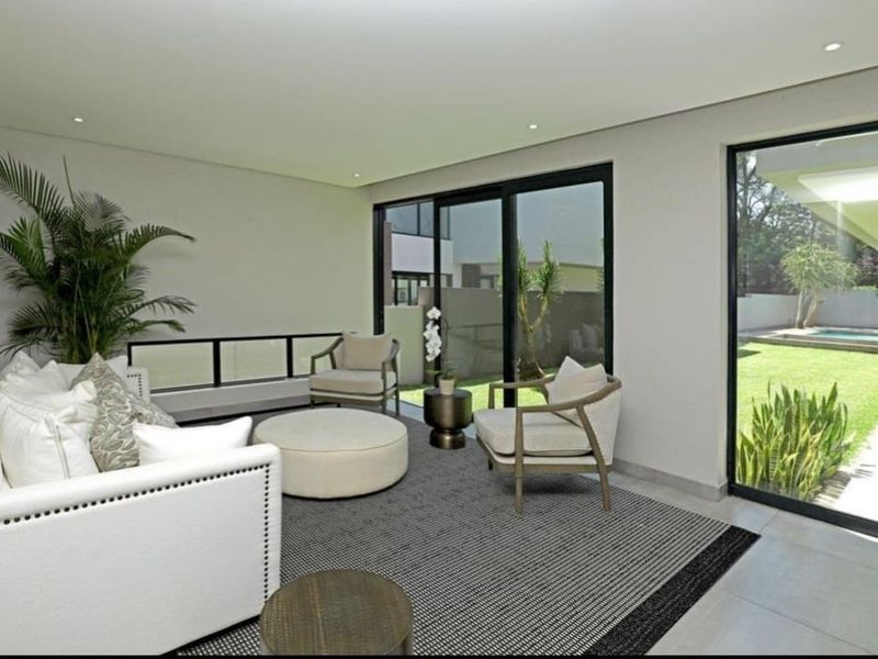 Bright and modern living room featuring large sliding glass doors that provide seamless access to the garden and pool area.