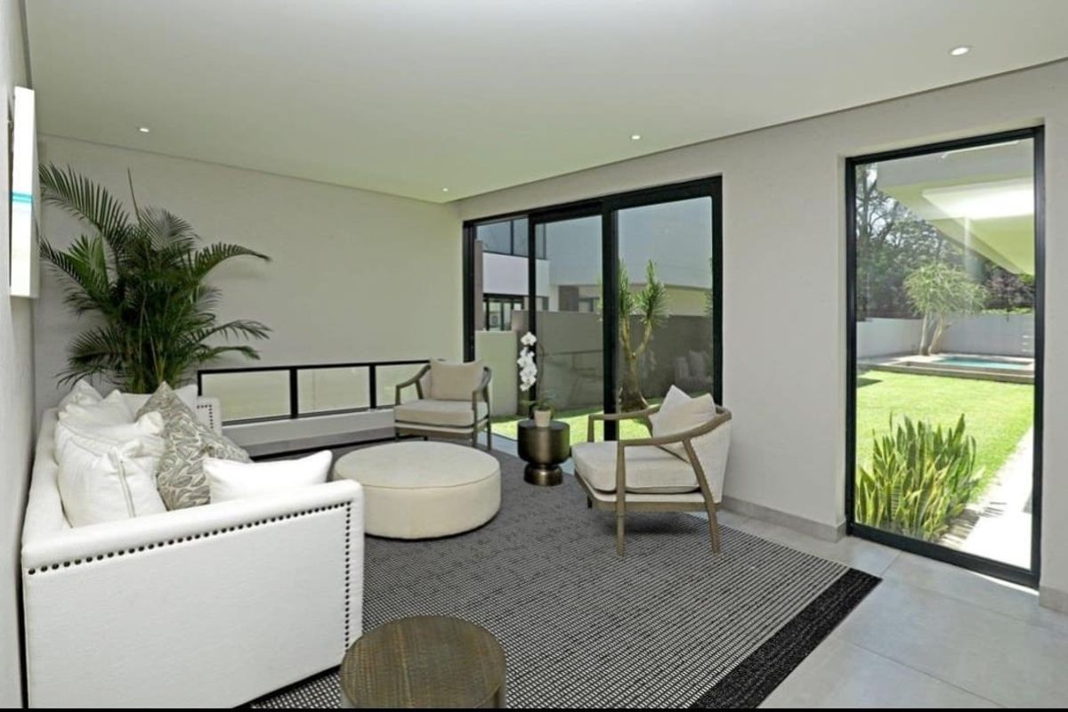 Bright and modern living room featuring large sliding glass doors that provide seamless access to the garden and pool area.