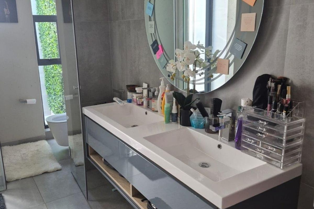 Modern bathroom featuring a sleek double vanity with integrated sinks, large format grey tiling, and a glass-enclosed shower area.