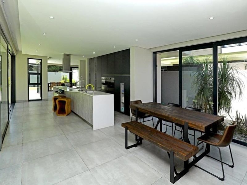 Modern open-plan kitchen and dining area featuring a sleek island, built-in appliances, and large sliding glass doors providing seamless access to the outdoor space.