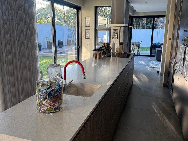 Modern kitchen featuring a large island with stone countertops, integrated cabinetry, and stainless steel extractor fan, opening directly to the rear garden.