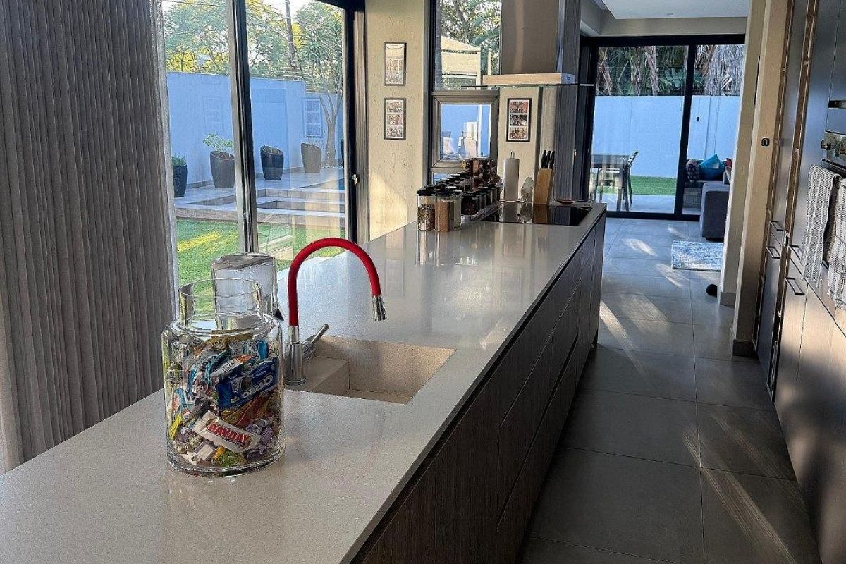 Modern kitchen featuring a large island with stone countertops, integrated cabinetry, and stainless steel extractor fan, opening directly to the rear garden.