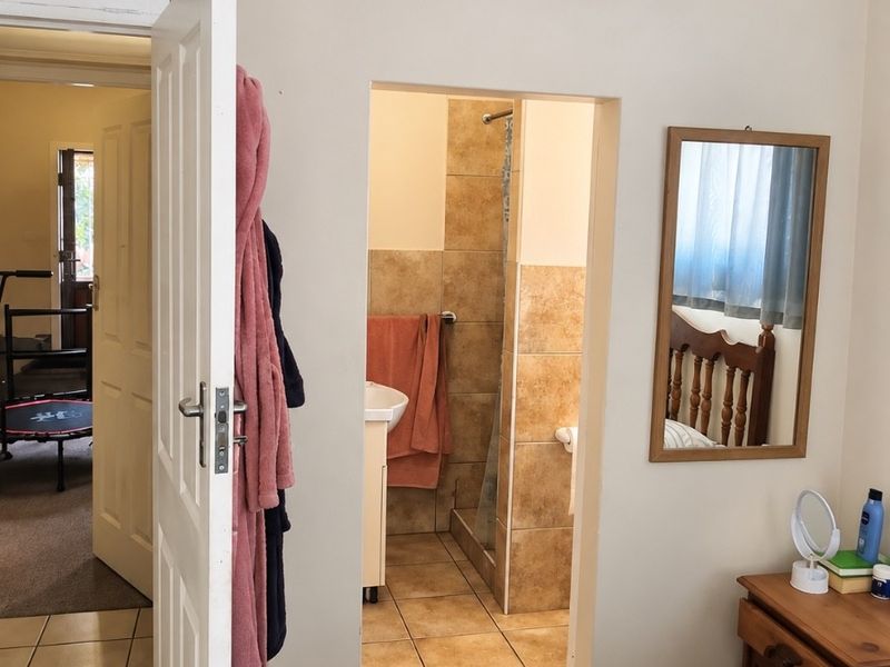 A bedroom featuring an en-suite bathroom with tiled finishes, a shower, and a pedestal basin, accessible via a standard door.