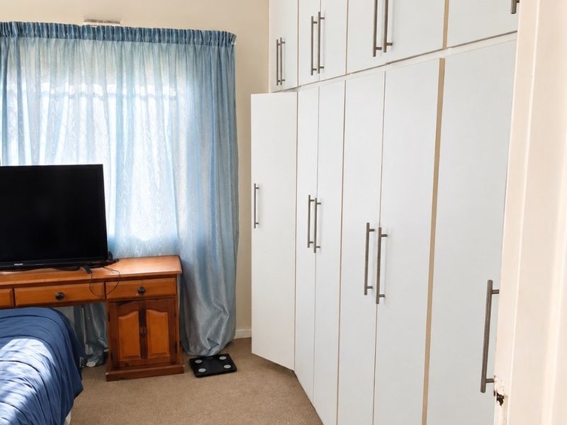 A bedroom featuring extensive floor-to-ceiling built-in cupboards and a ceiling fan, providing ample storage space.