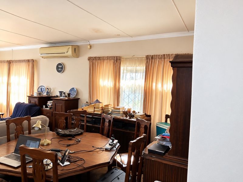 A living area featuring a wall-mounted air conditioning unit and coved ceilings, showing signs of minor ceiling water staining.