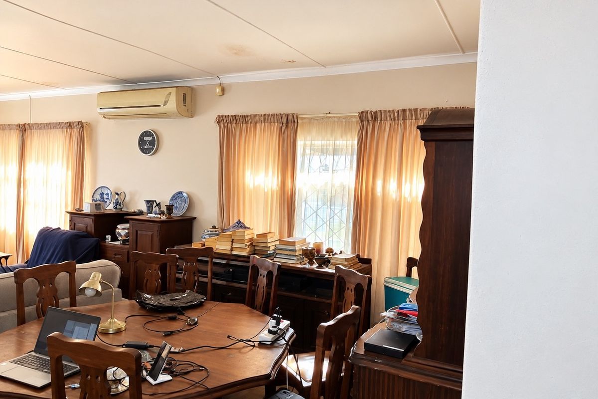 A living area featuring a wall-mounted air conditioning unit and coved ceilings, showing signs of minor ceiling water staining.