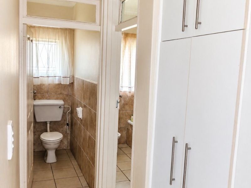 A functional hallway featuring built-in storage cupboards, tiled flooring, and direct access to a separate toilet area.