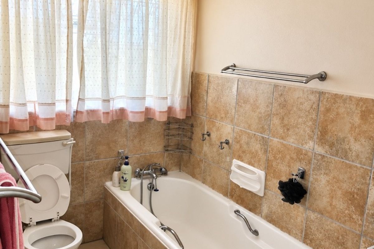 A functional bathroom featuring a bathtub, toilet, and neutral-toned wall and floor tiling, offering a classic layout ready for modern updates.