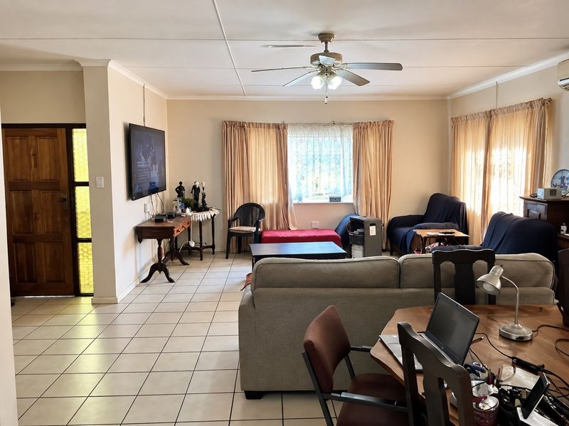 Spacious open-plan living area featuring tiled flooring, a ceiling fan, and neutral wall finishes, providing a versatile layout for dining and relaxation.
