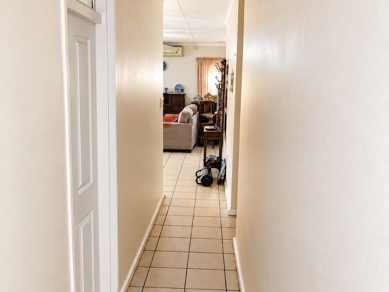 A functional hallway featuring tiled flooring and a ceiling access hatch, providing a clear transition between the home's living areas.