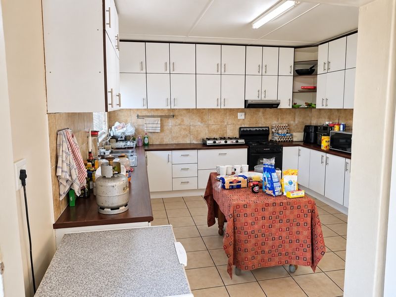 Functional kitchen featuring extensive white cabinetry, laminate countertops, tiled backsplash, and ceramic flooring, providing ample storage and workspace for daily meal preparation.