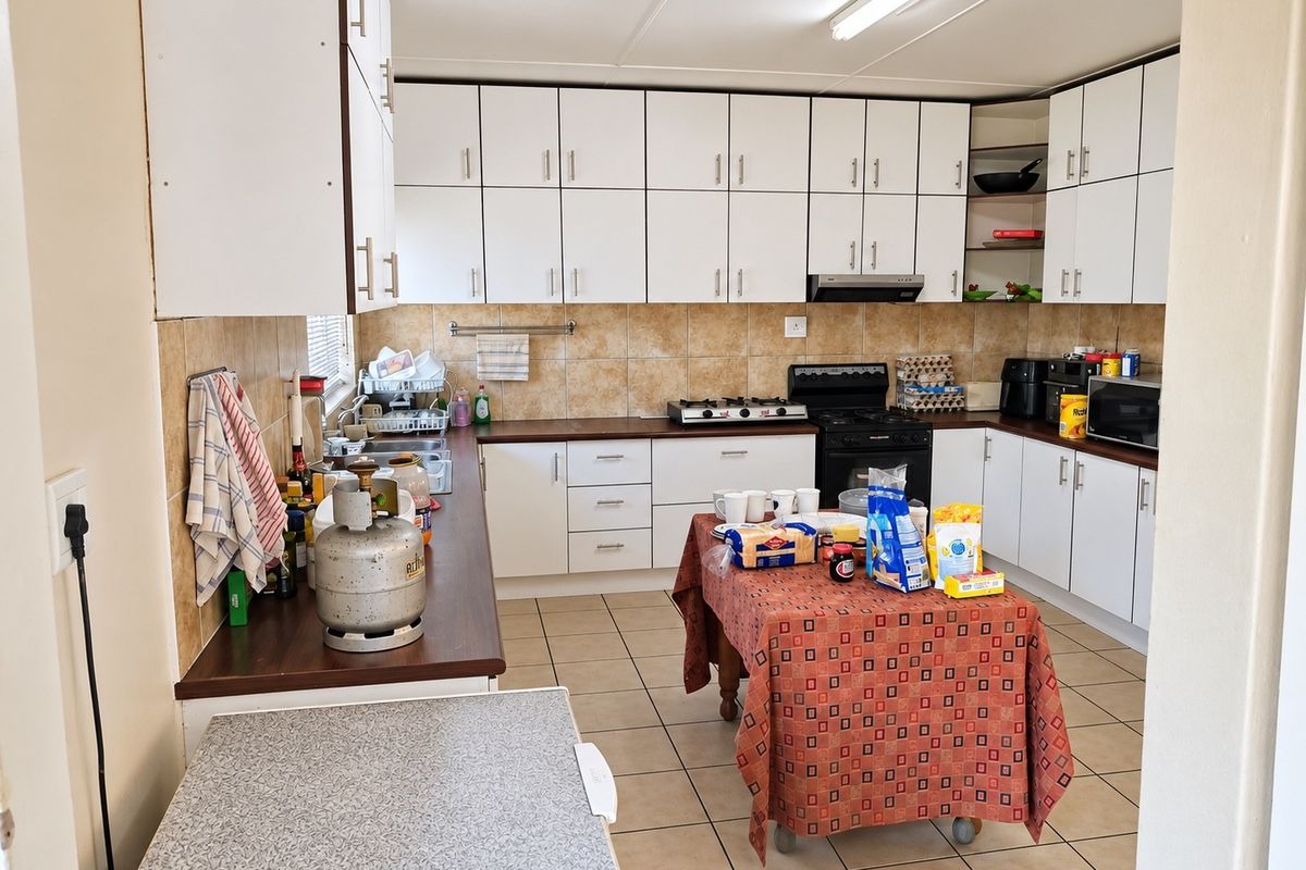 Functional kitchen featuring extensive white cabinetry, laminate countertops, tiled backsplash, and ceramic flooring, providing ample storage and workspace for daily meal preparation.