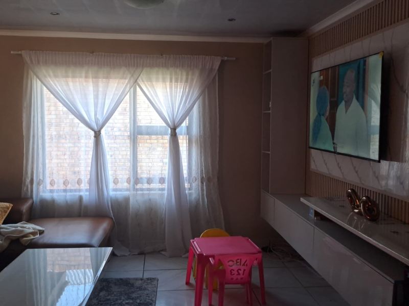 A comfortable living room featuring a modern built-in media unit with slatted wall detailing and tiled flooring.