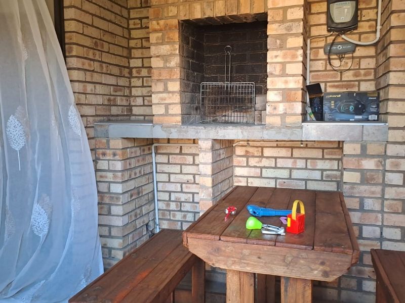 Covered patio area featuring a built-in brick braai and sliding door access to the interior.