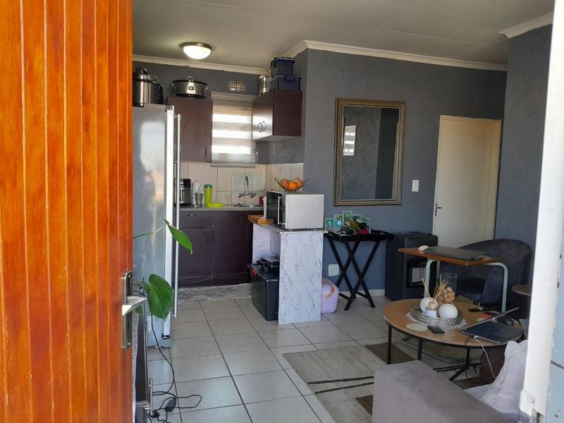 Open-plan living area featuring tiled flooring and a compact kitchen with built-in cabinetry, providing a functional layout for apartment living.