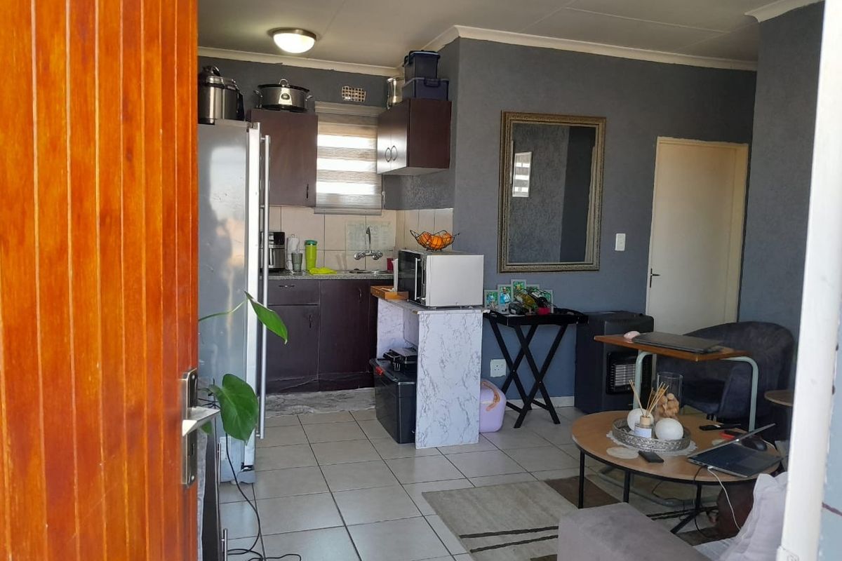 Open-plan living area featuring tiled flooring and a compact kitchen with built-in cabinetry, providing a functional layout for apartment living.