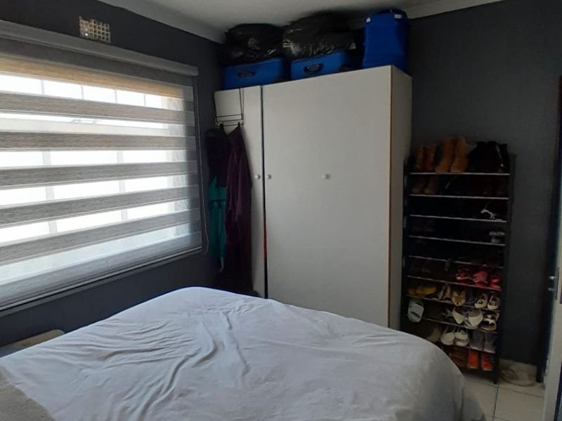 A functional bedroom featuring tiled flooring, a built-in wardrobe, and roller blinds, providing a practical living space.
